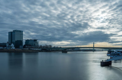 Bridge over river in city against sky