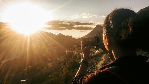 Rear view of woman using mobile phone against sky