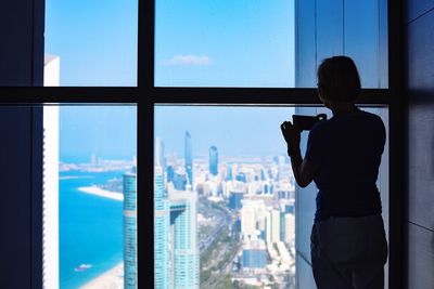 Rear view of man standing on glass window in city