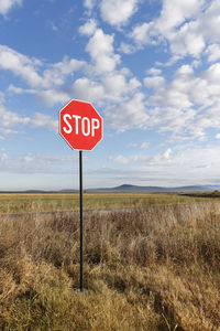 Information sign on field against sky