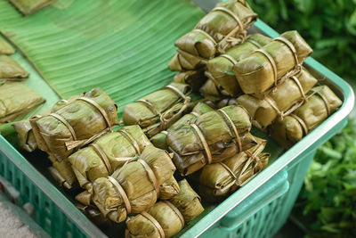 Selective focus on thai dessert of rice porridge wrapped by banana leaf in traditional market.