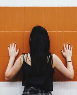 Rear view of woman standing against wall