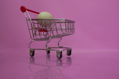 Side view of a pink candle on table against wall