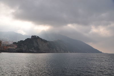 Scenic view of sea by mountains against sky