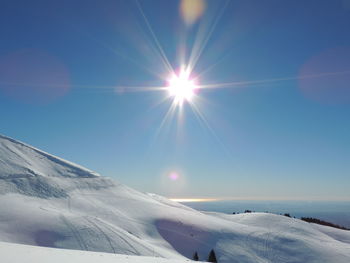 Scenic view of snow covered mountains against sky on sunny day