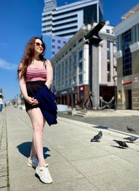 Full length of smiling woman standing in city