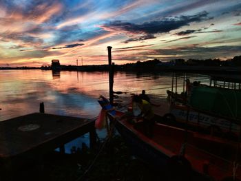 Boats moored at harbor against sky during sunset