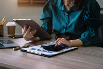 Midsection of man using digital tablet on table