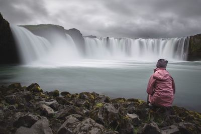 Rear view of man standing against waterfall