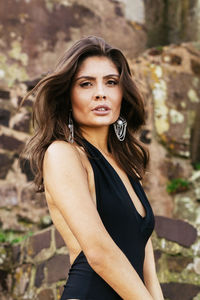 Beautiful young woman standing against stone wall