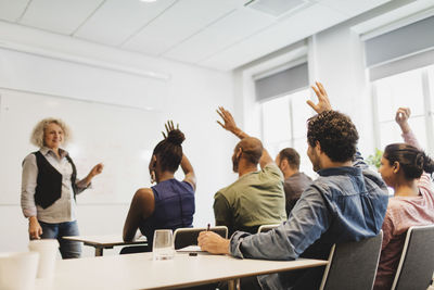 Students with arms raised looking at teacher in language class