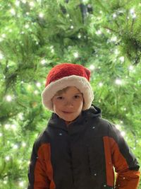 Portrait of smiling boy standing against trees during winter