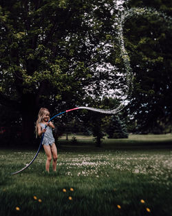 Girl playing on grass against trees