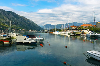 Pier with yachts and boats against a background of mountains with blue sky with clouds