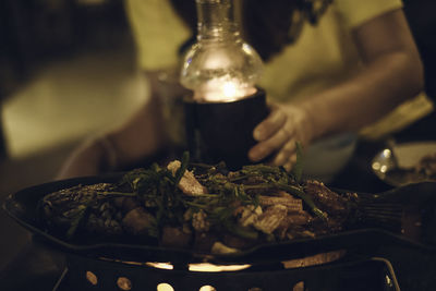 Close-up of food in plate on stove with woman in background