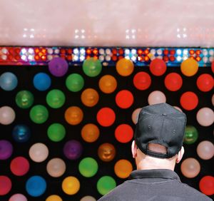 Rear view of man standing against colorful balloons on wall