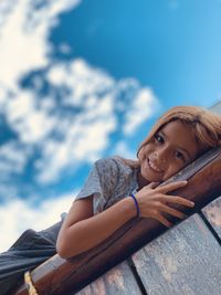 Low angle view of young woman sitting against sky