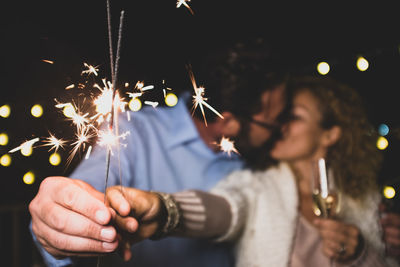 Midsection of man holding sparkler at night