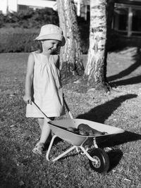 Black and white little girl laughing in the garden with a trolley