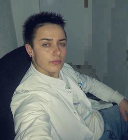 Portrait of young man sitting against wall at home