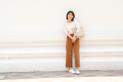 Portrait of woman standing against wall