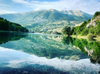 Scenic view of lake by mountains against sky