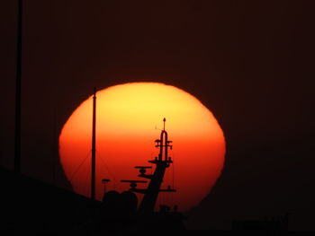 Silhouette cranes against orange sky