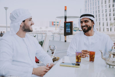 Smiling business people having discussion while sitting at cafe