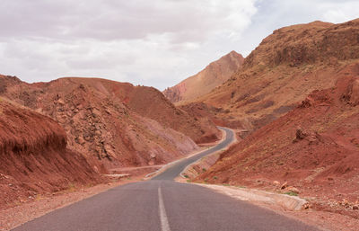 Empty road amidst mountains against sky