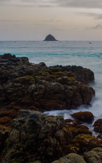 Rocks on sea shore against sky