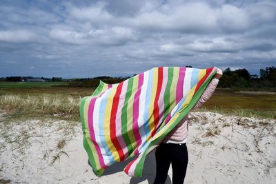 Rear view of woman standing on field against sky