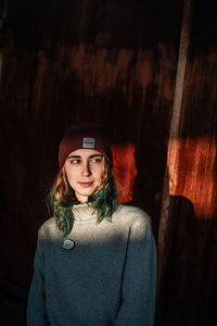 Portrait of beautiful young woman standing against wall