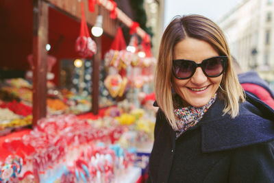 Smiling mature woman wearing sunglasses at market in city