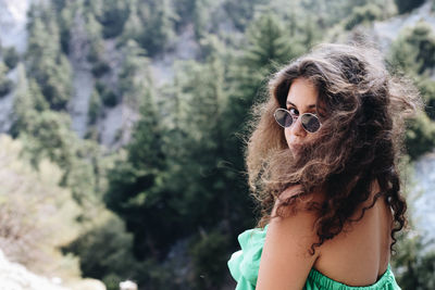 Portrait of woman wearing sunglasses while standing against mountain