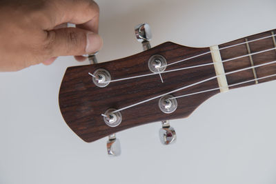 Close-up of hands playing guitar against white background