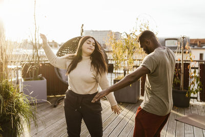 Carefree man and woman dancing together on terrace