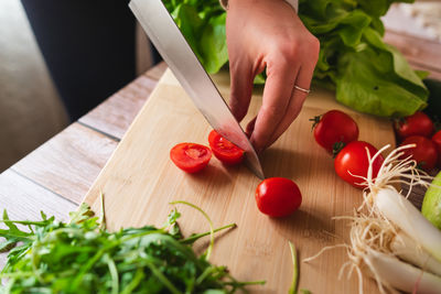 Cropped hand of person holding tomatoes on cutting board