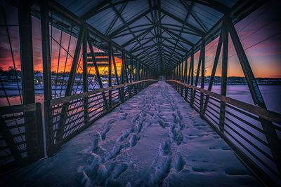 Snow covered bridge against sky during sunset