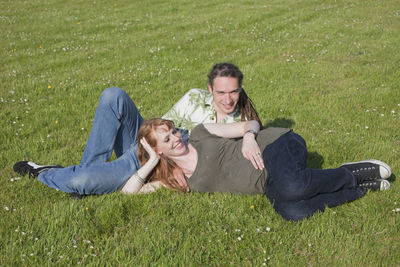 Pregnant woman with husband reclining on field at park