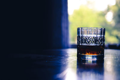 Close-up of whiskey in glass on table against window