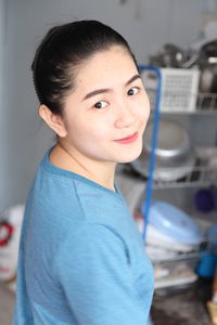 Portrait of smiling young woman standing in kitchen at home