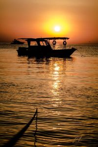 Silhouette boat in sea against sky during sunset