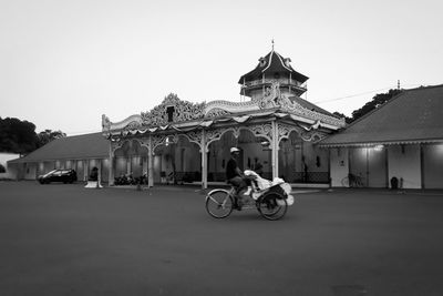 People riding motorcycle on street amidst buildings against sky