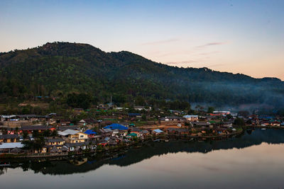 Scenic view of lake by buildings in town against sky