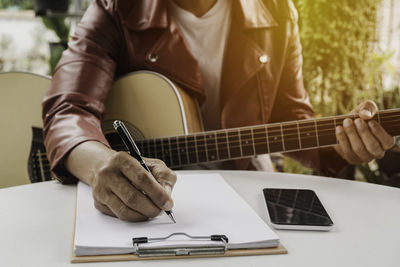 Midsection of man holding guitar on table