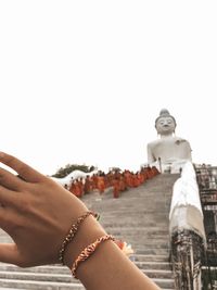 Midsection of woman with hands against clear sky