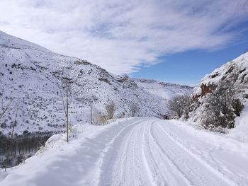 Road amidst snow covered mountains against sky