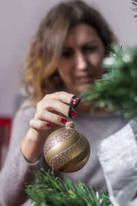 Woman decorating christmas tree at home