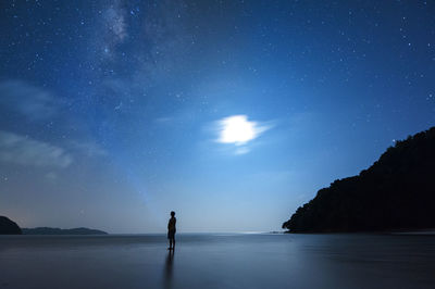 Silhouette man standing at beach against star field at night