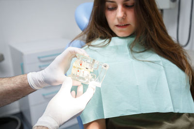 Professional doctor demonstration process of healthy teeth brushing to young woman sitting in chair.